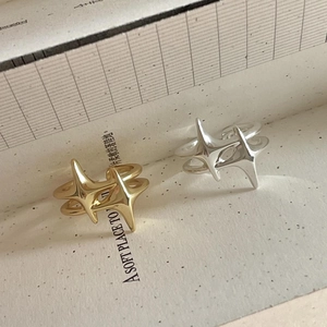 Artistic set of silver and gold star rings on textured paper with aesthetic shadows