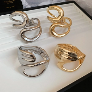 Close-up of irregular hollow geometric cuff bracelets in gold and silver with spring clasps