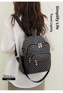 Detail of printed backpack featuring gold zippers and black handle for women