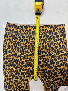 Measuring the rise of leopard print leggings with a yellow tape on a tiled surface