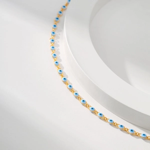 18K gold plated necklace with blue Evil Eye beads on a minimalist white display