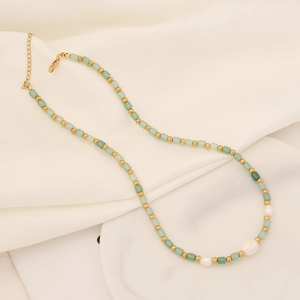 Collier de perles avec pierre naturelle vert clair et perles sur fond de satin blanc