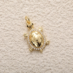 Macro detail of gold-plated turtle pendant with clear zircon inlay and geometric texture