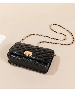 Detailed close-up of black quilted leather texture and gold chain strap on a women handbag