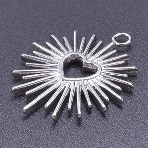 Macro shot of silver stainless steel heart pendant with radiant sunburst textured detail