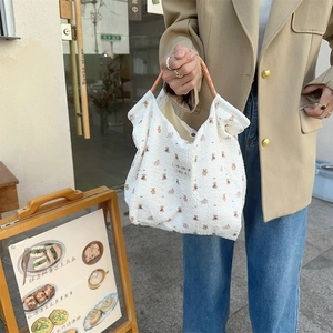 Detail of waffle fabric tote bag with brown bear patterns and orange handles