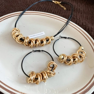Detail view of gold twisted metal rings with black leather cord on elegant ceramic tray