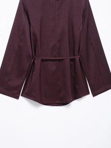 Detailed view of dark purple long sleeve satin shirt with waist belt and textured fabric