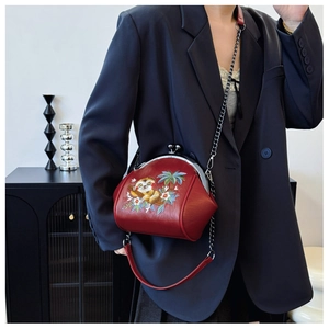 Detailed view of embroidery shell bag featuring sloth and floral patterns with chain strap