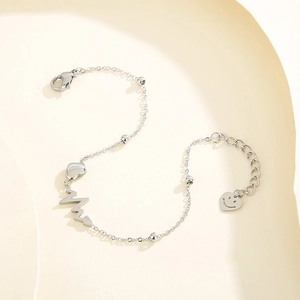 Silver stainless steel bracelet with heart, heartbeat and smiley face charms on beige background