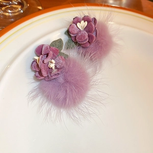 Detail of purple velvet flower earrings with fluffy pom-poms and delicate white stamen