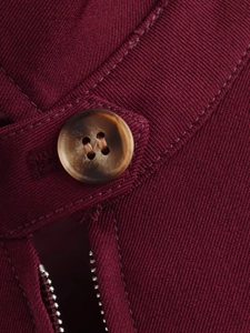 Close-up of wine red woven jacket featuring tortoiseshell button and metal zipper detail