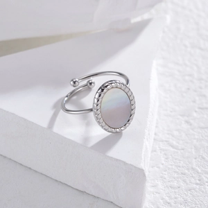 Détail de nacre blanche avec bordure torsadée sur bague réglable en acier