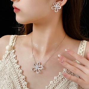 Gros plan d'un ensemble collier et boucles d'oreilles fleur évidée porté par un mannequin
