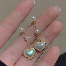 Detailed close-up of double heart pearl drop earrings with elegant golden plating