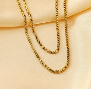 Detailed view of layered 18K gold plated mesh chain necklace on premium silk background