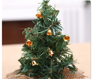 Miniature Christmas tree with golden bells and burlap base for festive table decoration