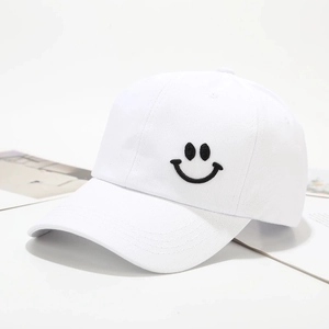 Detailopname van een witte katoenen honkbalpet met een zwart geborduurd smileygezicht