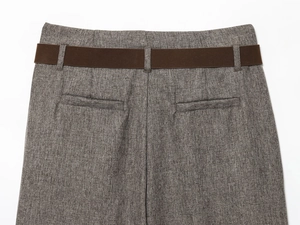Close-up of herringbone trousers with back welt pockets and brown textured belt