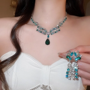 Detail view of a vintage silver necklace and earrings set featuring emerald green teardrop stones