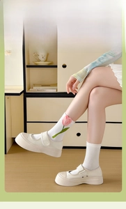 Detail of white cotton sock featuring wavy lace cuff and pink tulip embroidery design