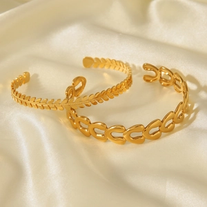 Detail of 18k gold plated open bracelets with leaf pattern and heart chain links on silk