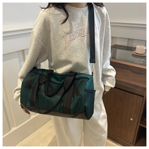 Detail view of large dark green mesh travel bag with black straps and side letter print