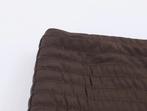 Détail macro du tissu matelassé marron foncé avec coutures soignées sur le vêtement