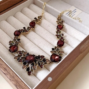 Detail of vintage necklace with red faceted gemstone and multicolored crystals in a box