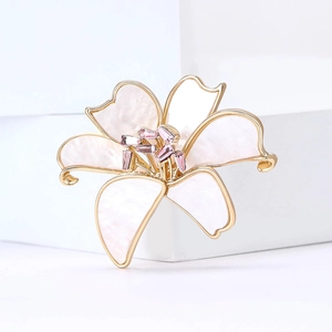 Macro detail of lily brooch with white shell petals and pink crystal center