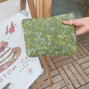 Detailed embroidery of delicate white and yellow flowers on a forest green makeup bag