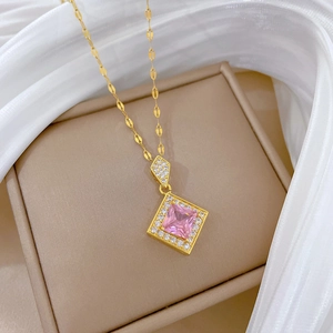 Detailed close-up of a gold necklace featuring a pink square crystal pendant on silk fabric