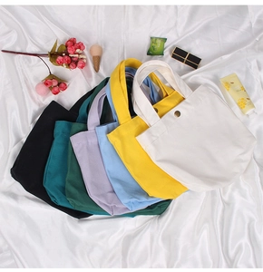 Flat lay of colorful canvas tote bags with metal snaps on satin background