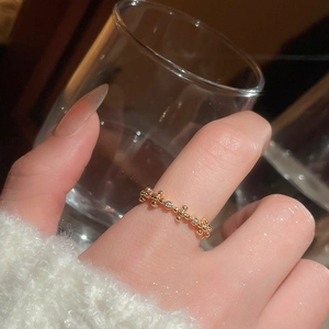 Detail of 18k gold plated ring with white zircon on hand holding a glass cup