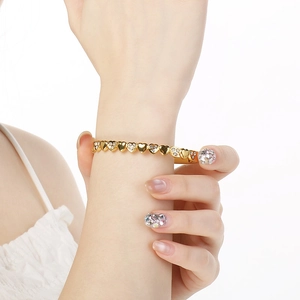 Close-up of a gold heart bracelet with sparkling diamonds worn on a woman's wrist