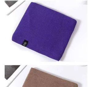 Detailed view of soft ribbed knit texture on purple winter scarf with stitched label