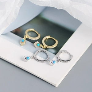 Close-up of gold and silver opal hoop earrings with blue stones and white zircon crystals