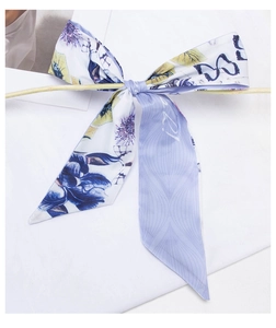 Close-up of a floral silk scarf tied in a bow on a branch with butterfly patterns