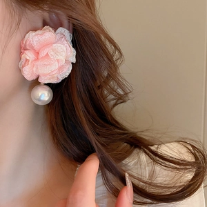 Close-up of a model wearing large pink fabric floral earrings with white pearl pendants