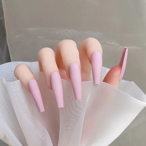 Gros plan de faux ongles ballerine longs rose mat sur main de modèle avec voile