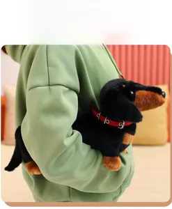 Close-up of a soft plush dachshund dog toy with a red collar held in a warm home setting