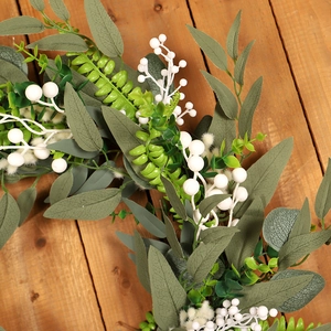 Artificial white berry and eucalyptus leaf wreath on rustic wood background for Christmas décor