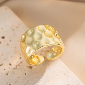 Gold-plated minimalist ring with hammered texture on a natural stone background