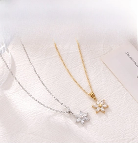 Detailed macro view of two floral necklaces with zircon petals in gold and silver finishes