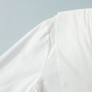 Detail shot of breathable white cotton linen fabric showing fine texture and shoulder seams