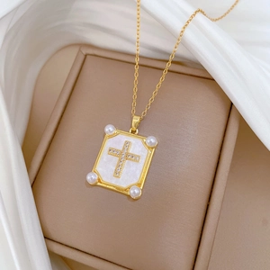 Detailed close-up of a pearl and diamond cross pendant on a gold necklace with shell inlay