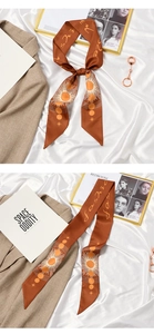 Detail of terracotta silk ribbon featuring sun and moon prints and elegant cursive text