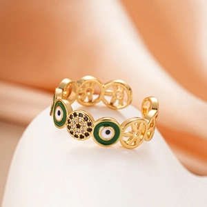 Detail of 18K gold ring with green enamel evil eye and pavé zircon on pink backdrop
