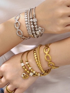 Détail de bracelets superposés en or et argent avec un pendentif cœur et gravure Love