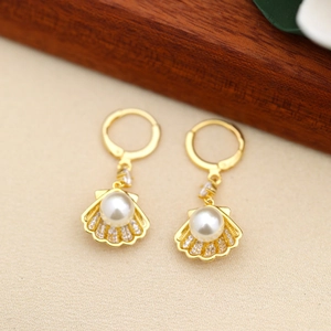 Detailed view of shell-shaped gold earrings with white pearls and small diamonds
